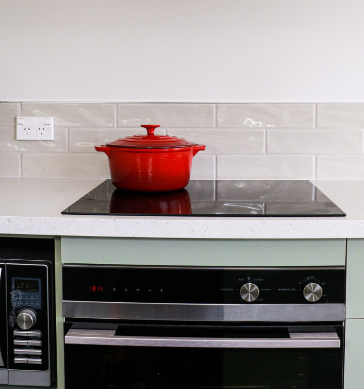 Close up of red dish on cooktop with oven