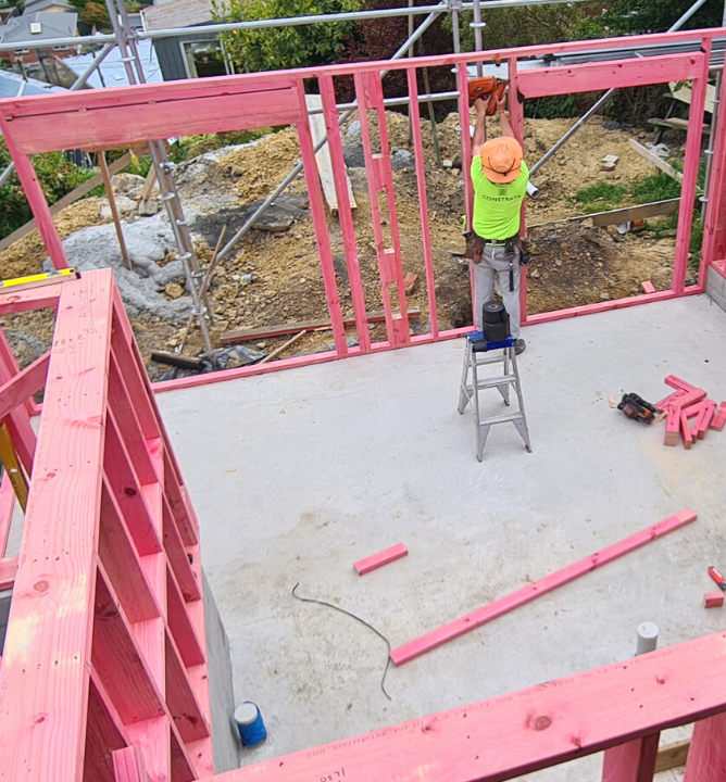 Top down view of a builder working in a new, framed up extension on concrete pad