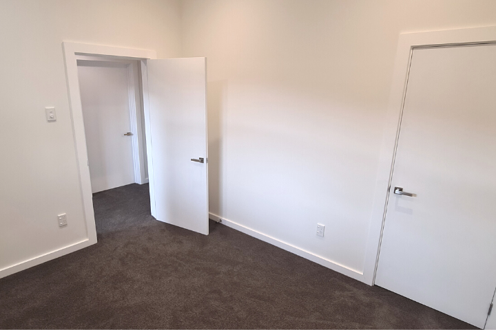 Renovated white bedroom with new grey carpet and updated doors and fittings